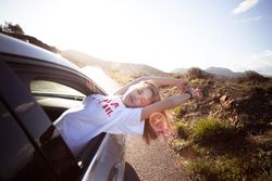 Joyful blonde woman leaning out of car window