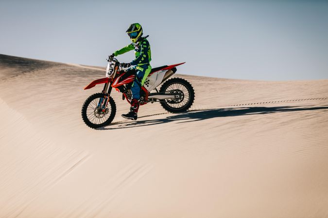 Dirt biker about to go down hill in desert