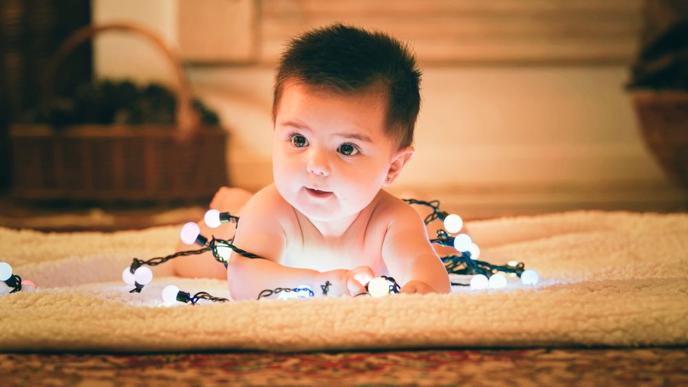 Baby playing with light garland on Christmas Day