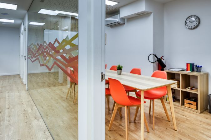 Interior of light corridor among glass walls in modern office with colorful furniture