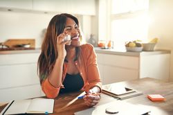 Businesswoman smiling while taking a call at her kitchen table