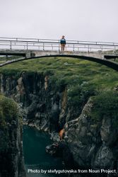 Man on bridge over rugged terrain bErOV0
