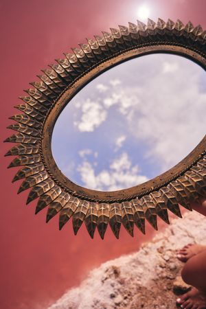 decorative mirror above pink lake water