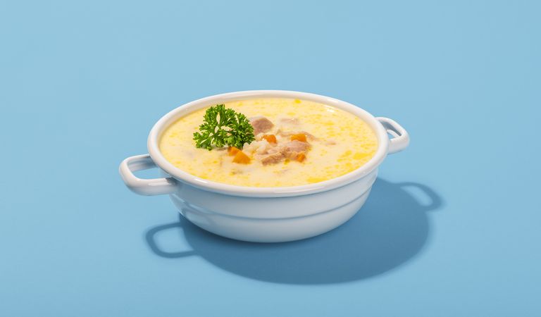 Greek soup in a bowl, minimalist on a blue table