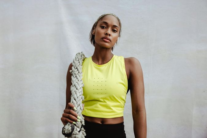 Fit woman in sportswear standing with battle rope