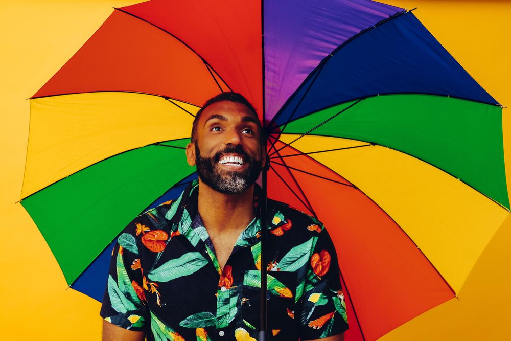 Happy man looking up from under colorful umbrella