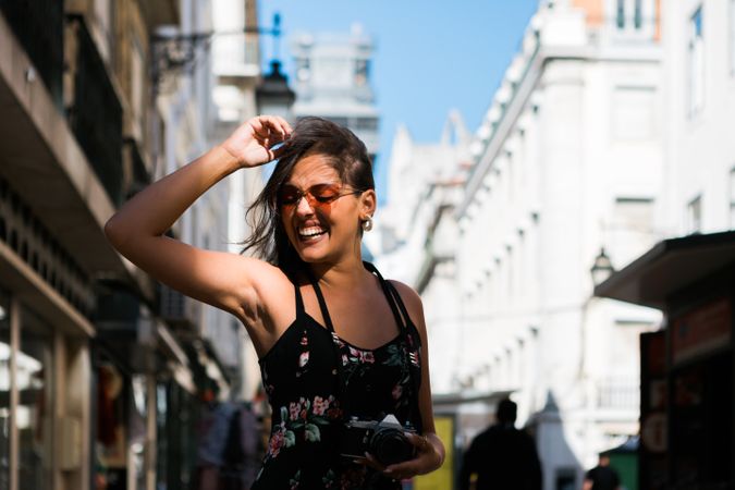Carefree woman holding a camera on the street
