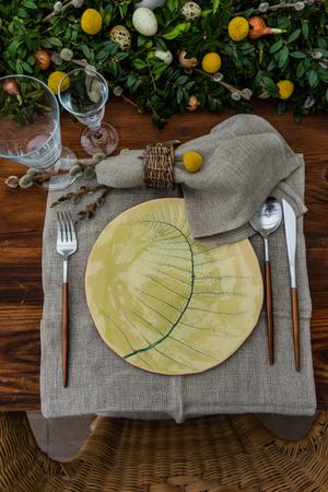 Festive table setting for Easter holiday dinner decorated with flowers and eggs on wooden table