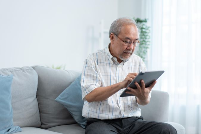 Mature male sitting at home with digital tablet