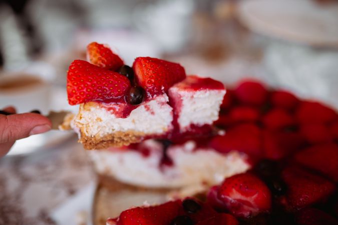 woman's hand cutting strawberry cake with knife