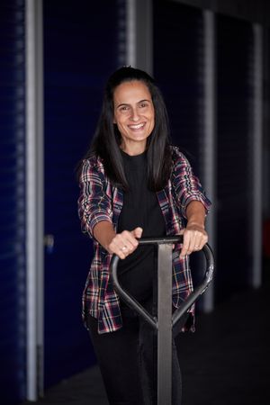 Young woman with moving wheelbarrow organizing her storage room