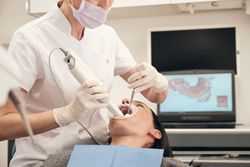 Crop stomatologist scanning teeth of woman in clinic