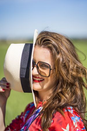 Cheerful woman in sunglasses looking at camera on sunny day