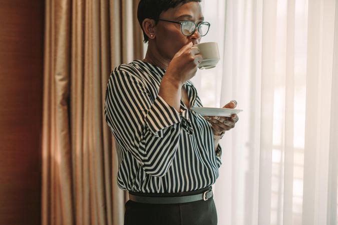 Woman in business wear having coffee in hotel room
