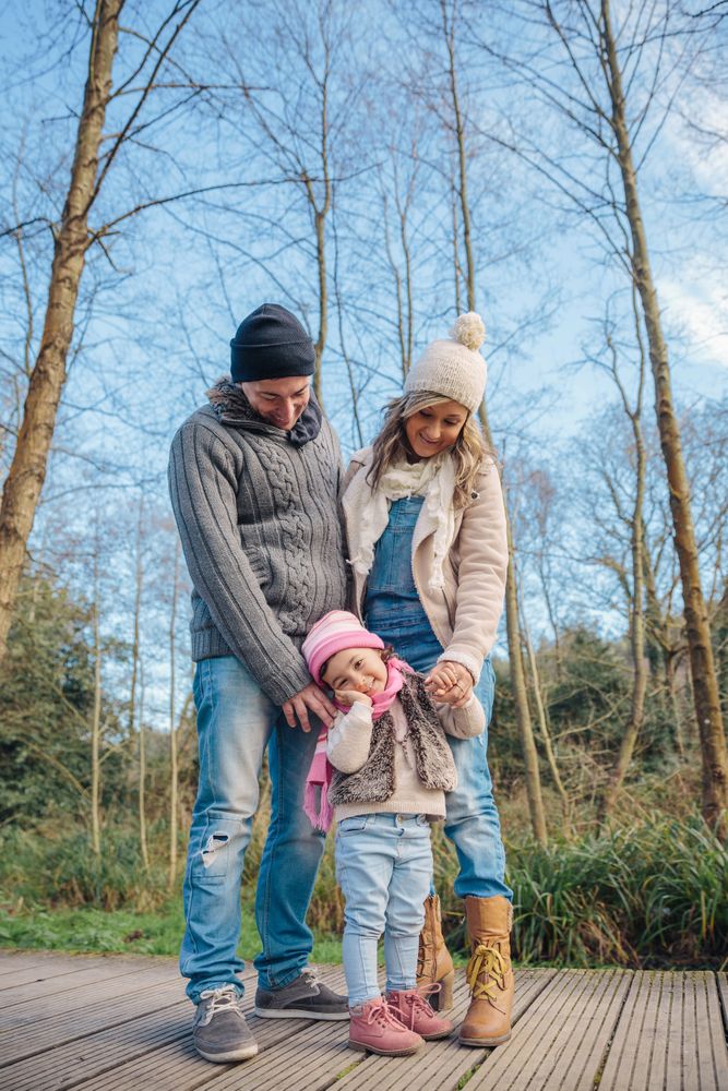 Mother and father standing with young daughter in forest
