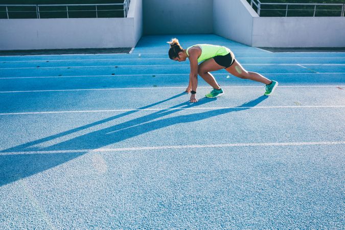 Young woman in starting position on a track field