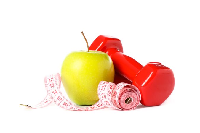 Dumbbells, measuring tape and apple isolated on plain background