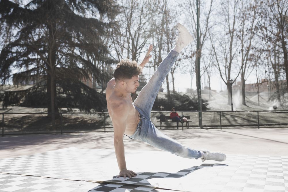 Shirtless man dancing break dance in park