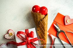 Red heart ornaments in waffle cone with envelope and gift on grey background 48BBJY