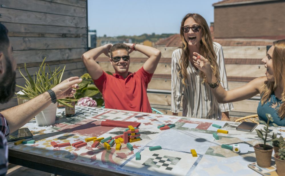 Office workers playing with tower wooden stacking on terrace