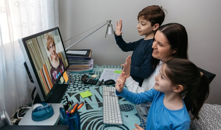 Family waving on video call with grandmother