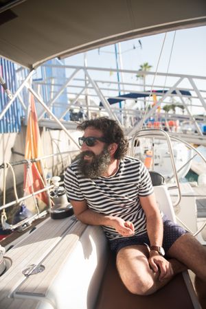 Smiling man sitting in yacht on quay
