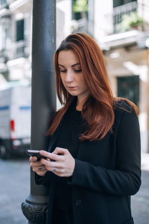 Woman looking down at smart phone on street