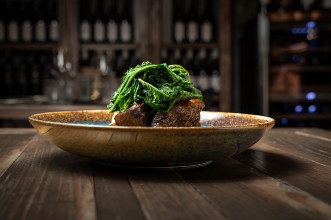 Braised beef with sautéed greens served in rustic ceramic plate
