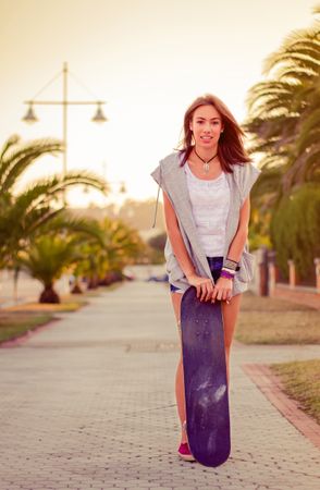 Young girl with a skateboard outdoors on summer