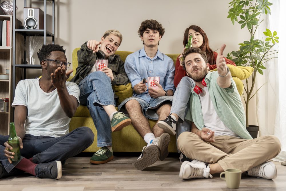 Group of multiracial young friends cheering and eating popcorn together during a home movie night