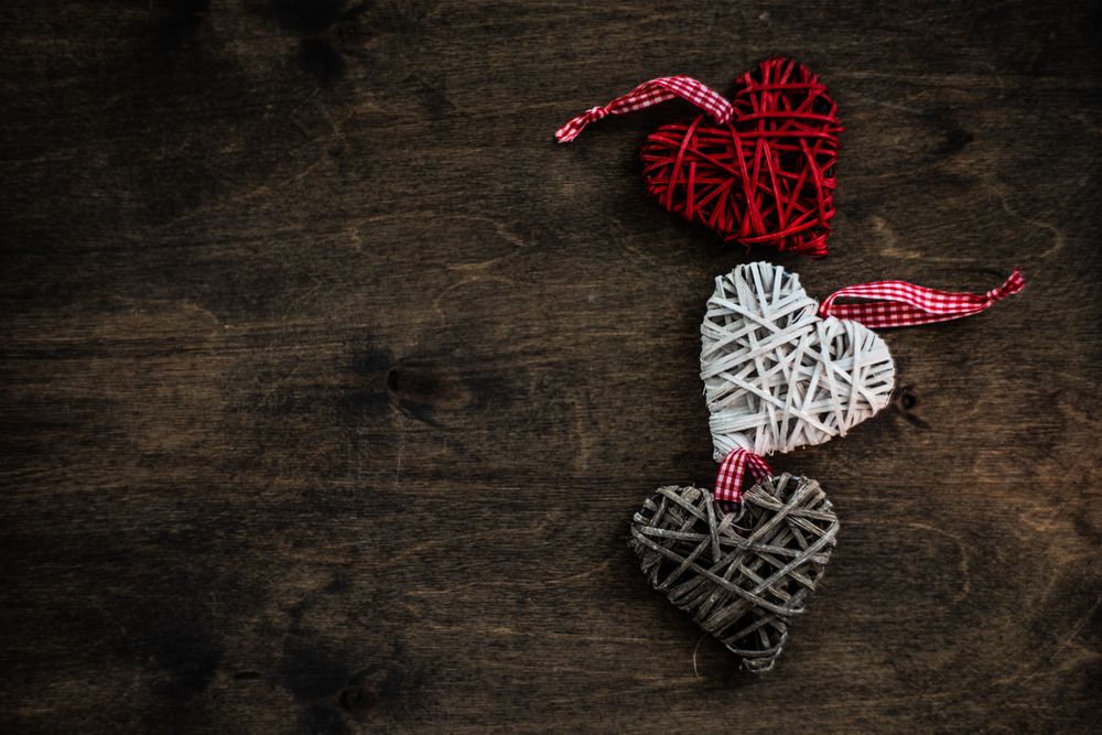 Valentine's day concept of thatched heart decorations on wooden table with space for text