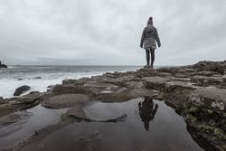 Female standing on cliff and contemplating