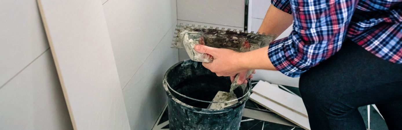 Unrecognizable female bricklayer taking cement from bucket