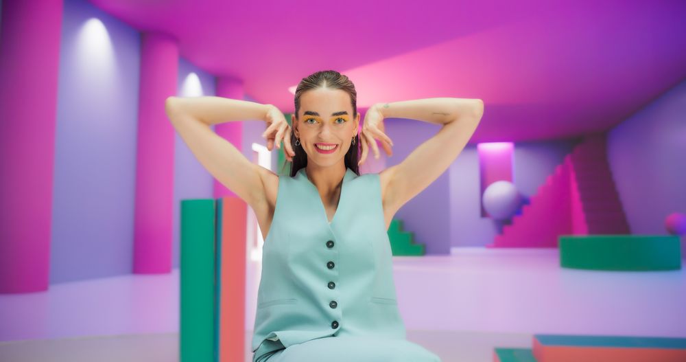 Woman with Bright Makeup Dancing Energetically and Interacting with Colorful Geometric Abstract Environment. Creative Young Female Happily Performing Modern Dance with Hand Movement
