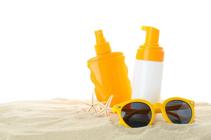 Sunscreens with starfish and sunglasses on clear sea sand isolated on blank background. Summer vacation