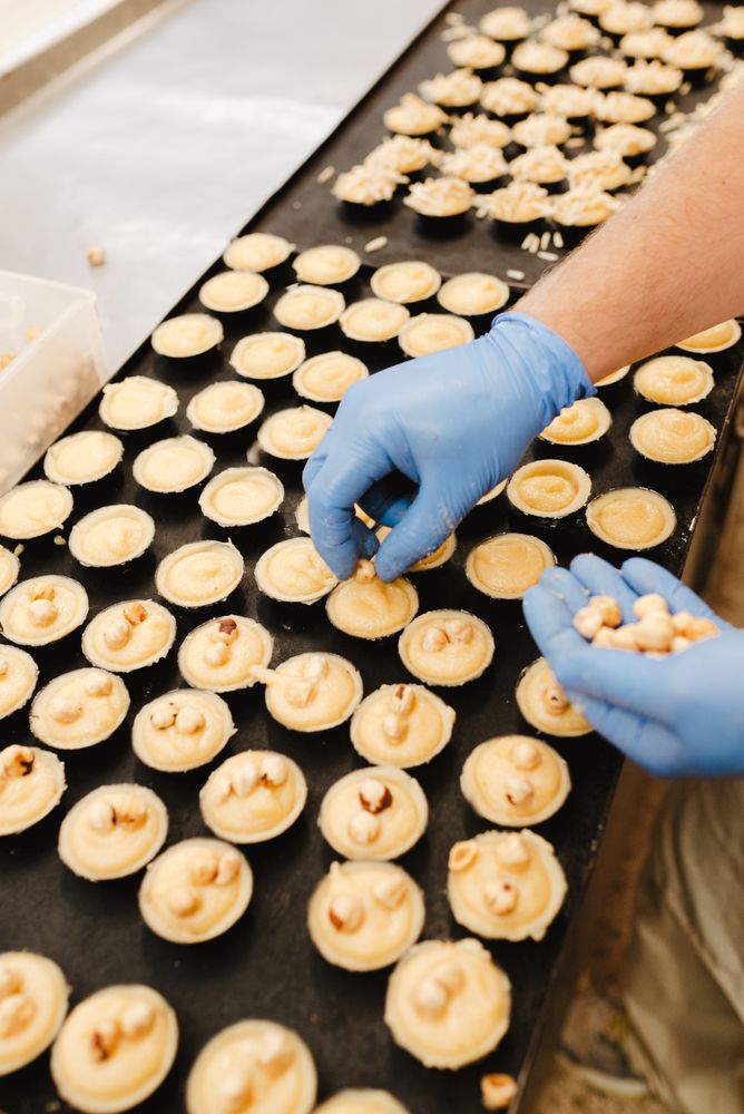 Crop confectioner decorating patisserie with nuts