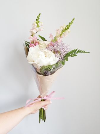 Flower bouquet held by a person with gray background