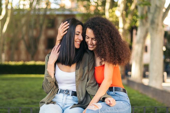 young female couple sitting together in park