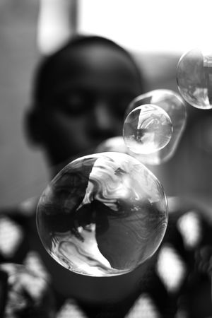 Grayscale photo young boy playing with soap bubbles in close-up