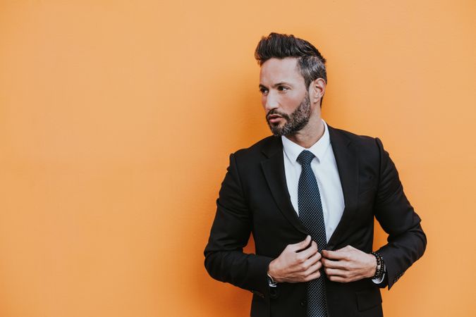 Adult stylish man in costume near orange wall