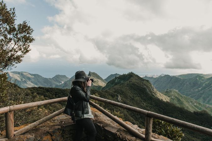 Young stylish woman taking photo on camera of wonderful mountains