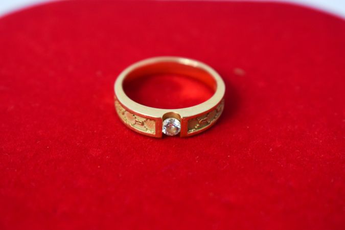 Man's diamond gold ring on red fabric with copy space