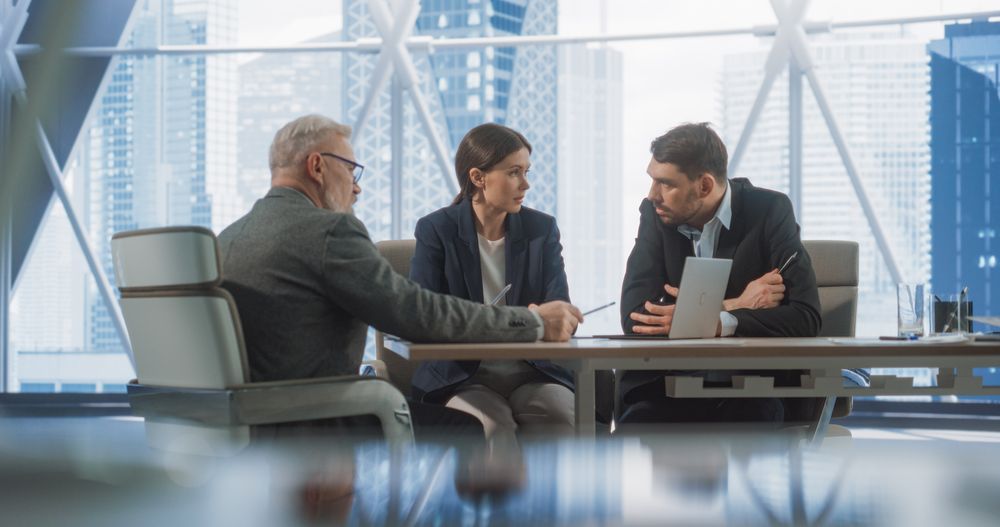 Corporate Office Conference Room: Three Diverse Male and Female Businesspeople Talking, Discussing Investment Opportunities, Using Laptop.