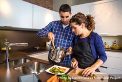 Woman cutting vegetables while her husband stands next to her with the pot 4BzLB4