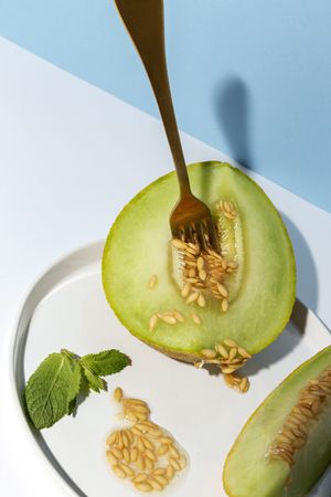Sliced small melon on plate with spoon and fork
