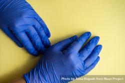 Top view of yellow table with hands wearing protective blue gloves 5aXn3G