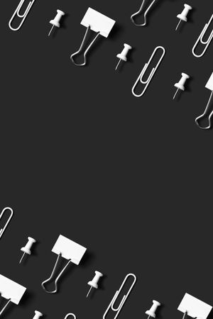 Paper clips, pushpin and binder clips over dark background with copy space
