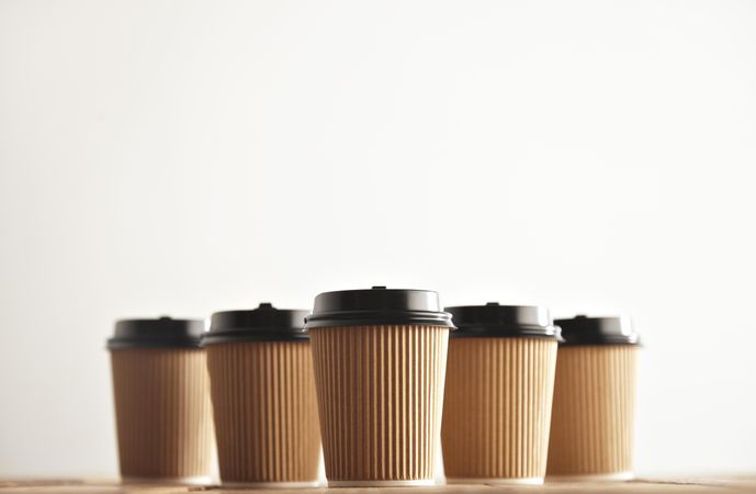 Five to go coffee cups in row on wooden table