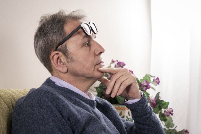 Mature man with flip-up glasses thinking and contemplating at home.