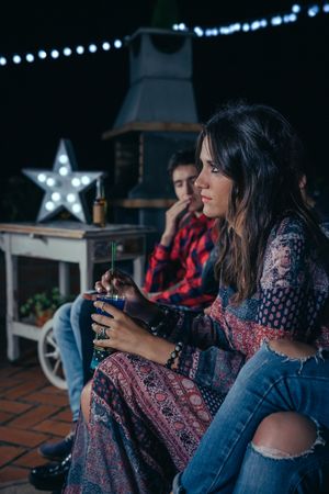 Thoughtful woman holding cocktail with her friends in party